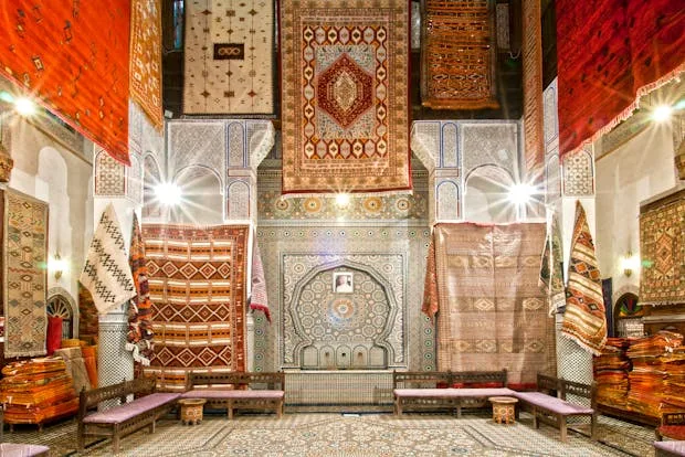 Handwoven Moroccan rugs on display in a vibrant bazaar.