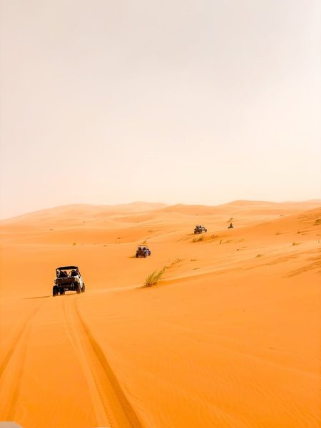 Thrill-seekers driving quad bikes and buggies through the desert dunes on a 10 day Morocco itinerary.