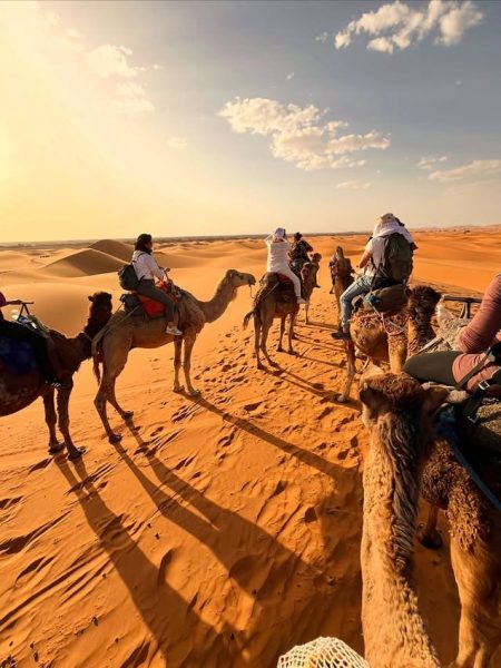 Traveler enjoying a camel trek across the Sahara desert in Merzouga
