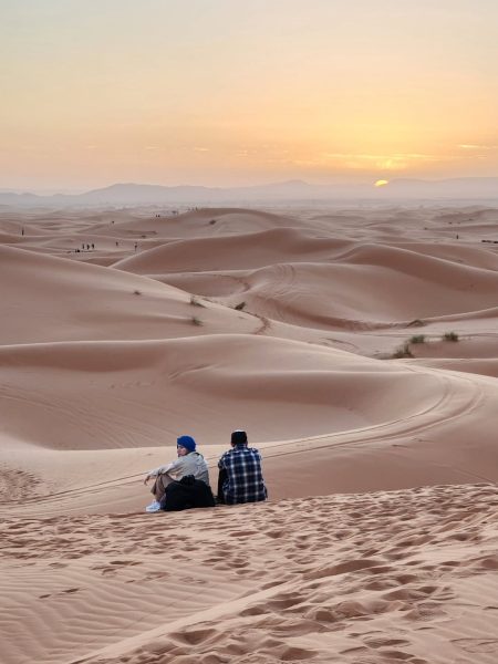 Travelers watching the sunset over the golden dunes of Merzouga on a 5-day tour from Casablanca