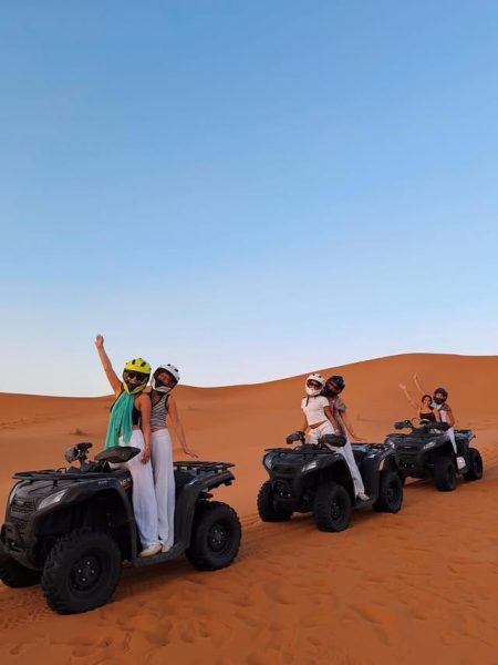 Adventure travelers riding quad bikes through the sandy trails of Erg Chebbi desert in Morocco